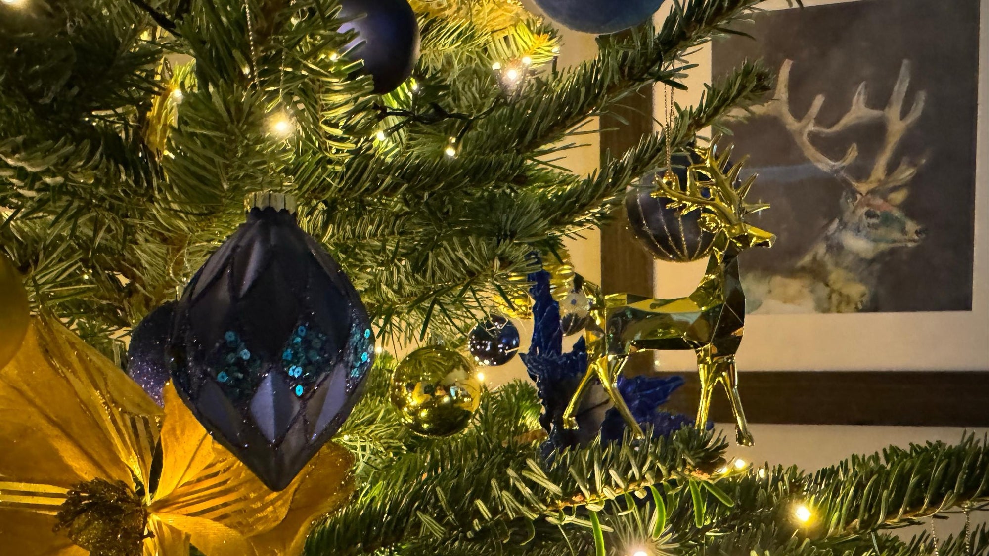 Real Nordmann Fir decorated with blue and gold baubles and a gold stag ornament